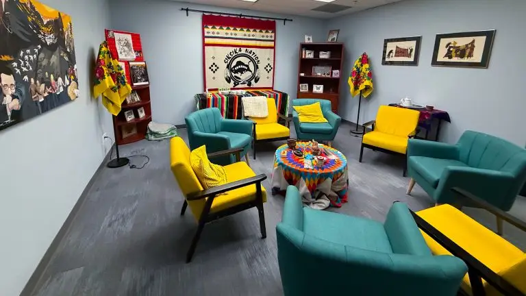 An image of the nii Moyis (“Buffalo Lodge”) Cultural Room at Calgary Legal Guidance. It has comfortable seating, lost of different pieces of indigenous art works.